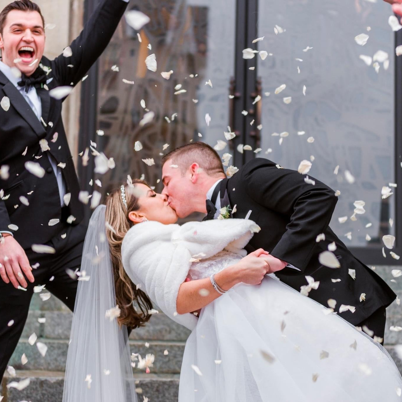 Bulk Ivory Rose Petals for weddings – Prime Petal Company. Bulk ivory rose petals for elegant wedding aisle and event décor – Prime Petal Company. Wedding couple kissing with biodegradable confetti falling around them.