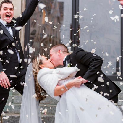 Bulk Ivory Rose Petals for weddings – Prime Petal Company. Bulk ivory rose petals for elegant wedding aisle and event décor – Prime Petal Company. Wedding couple kissing with biodegradable confetti falling around them.