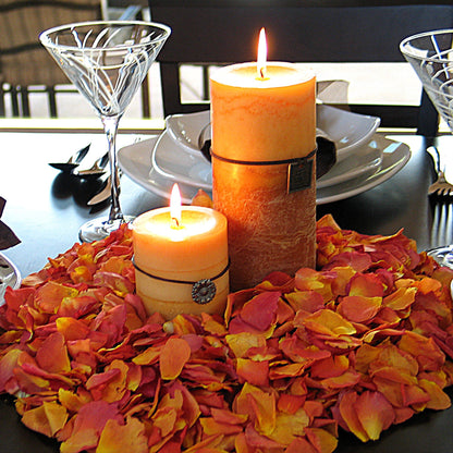 Bulk orange ombre gradient rose petals for fall weddings – Prime Petal Company. Decorative table setting with candles and rose petals on a dark surface