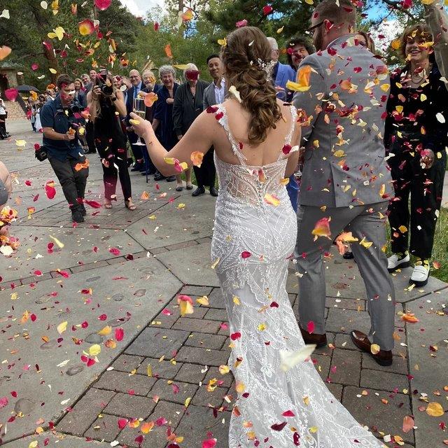 Bulk yellow rose petals for bright wedding aisle and party décor – Prime Petal Company. Wedding couple walking through rose petal confetti with guests in a park setting