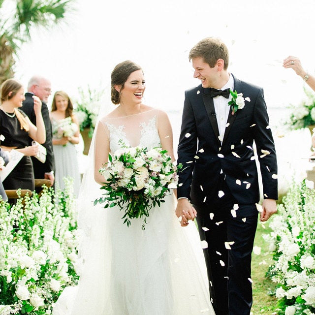 Bulk ivory rose petals for elegant wedding aisle and event décor – Prime Petal Company. Wedding couple walking together with confetti around, surrounded by floral decorations.