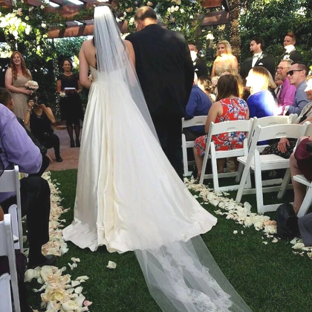 Bulk ivory cream blush rose petals for soft-toned wedding décor – Prime Petal Company.  A Wedding ceremony with a bride and groom at an outdoor venue.