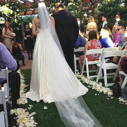 Bulk ivory cream blush rose petals for soft-toned wedding décor – Prime Petal Company.  A Wedding ceremony with a bride and groom at an outdoor venue.