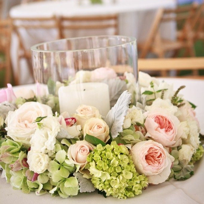 Bulk green hydrangea petals for wedding and event décor – Prime Petal Company. Floral centerpiece with hydrangea petals, roses, and candles on a table in an outdoor setting