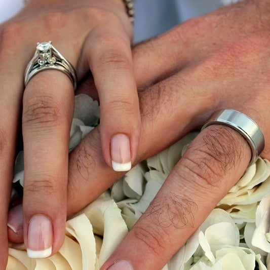 Bulk Irish Blend green hydrangea and ivory rose petals for weddings – Prime Petal Company. Close-up of two hands with wedding rings on a white floral background