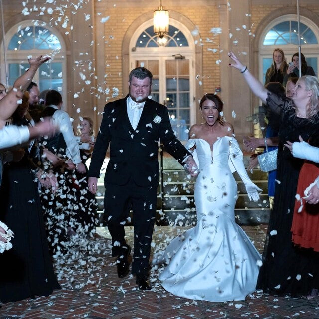 Bulk Ivory Rose Petals for weddings – Prime Petal Company. Bulk ivory rose petals for elegant wedding aisle and event décor – Prime Petal Company. A wedding couple walking down a staircase with rose petal confetti falling around them.