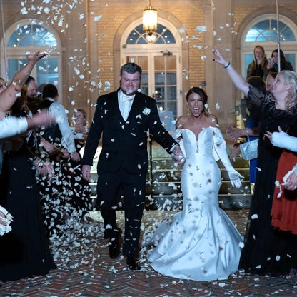 Bulk Ivory Rose Petals for weddings – Prime Petal Company. Bulk ivory rose petals for elegant wedding aisle and event décor – Prime Petal Company. A wedding couple walking down a staircase with rose petal confetti falling around them.