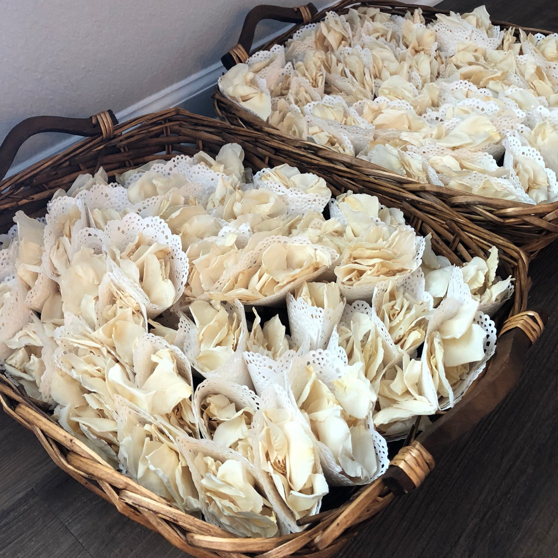 Bulk Irish Blend green hydrangea and ivory rose petals for weddings – Prime Petal Company. Two wicker baskets filled with petal cones for guest tossing at a wedding.