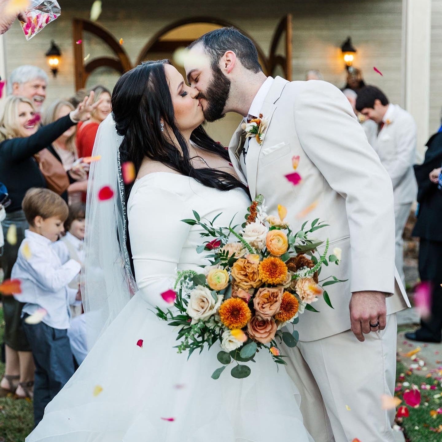 Couple kissing at a wedding with a colorful bouquet and confetti. Bulk Peppermint Twist rose and hydrangea petal blend for weddings – Prime Petal Company
