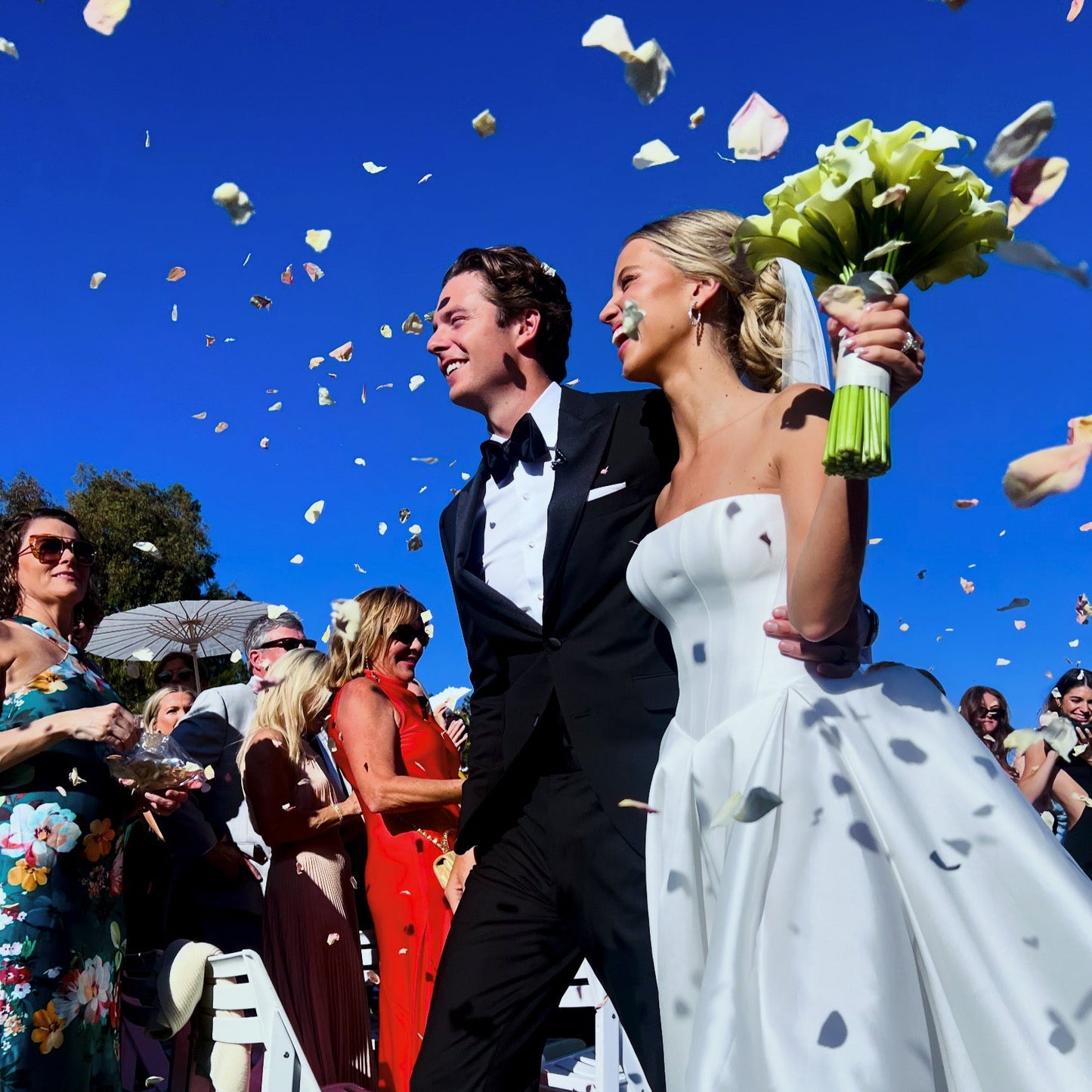 Bulk Wine Green Hydrangea Petals for weddings – Prime Petal Company. Wedding couple celebrating with Primw Petal biodegradable confetti against a blue sky