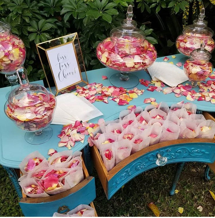 Bulk Blissful Bloom mixed flower petals for weddings and events – Prime Petal Company. Decorative table with rose petal confetti and candy jars outdoors.