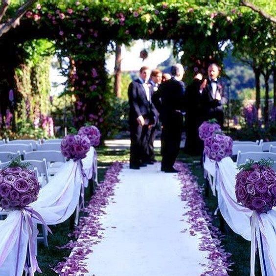 Bulk purple rose petals for wedding celebrations and event décor – Prime Petal Company. Wedding ceremony with purple rose petals and floral arrangements along a wedding aisle and under a floral archway.