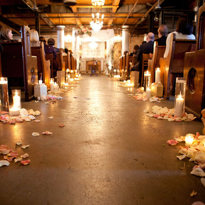 Bulk ivory rose petals for elegant wedding aisle and event décor – Prime Petal Company. Candle-lit aisle with scattered rose petals